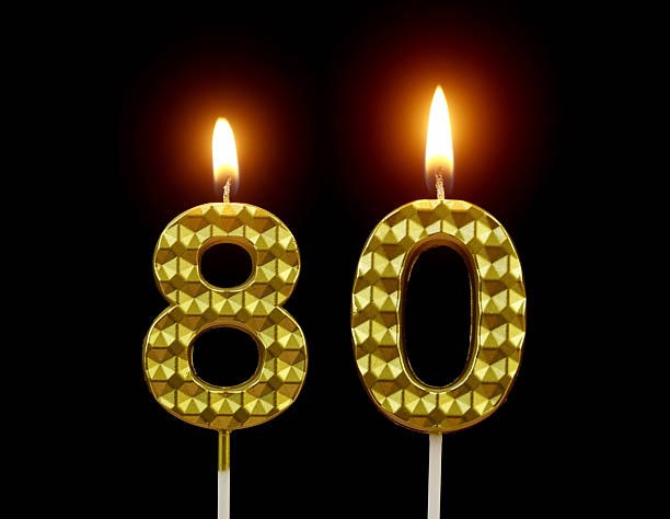 istock Gold birthday candles burning on black, number 80. 2211893982