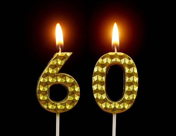 istock Gold birthday candles burning on black, number 60. 2211893988