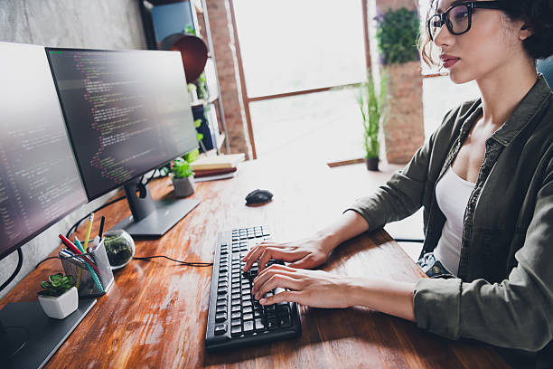 istock Young female programmer working at a computer desk in a casual home office environment developing software code professionally 2211894019