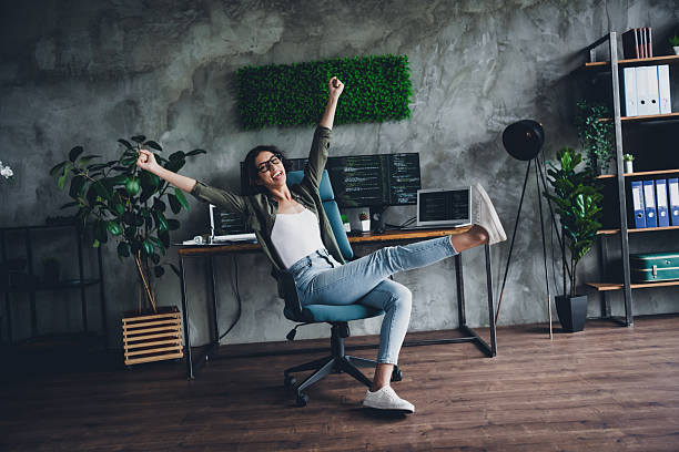 istock Young female programmer celebrates a break in her workspace with a cheerful pose, showcasing a casual and vibrant office environment. 2211894140
