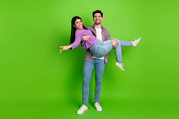 istock Joyful couple bonding in a playful pose over a bright green background, radiating happiness and showcasing love 2211894265