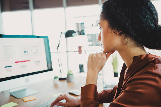 istock Young professional woman working in an office with natural light and modern design, analyzing data on her computer screen 2211895030
