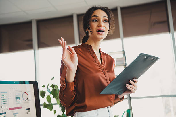 istock Young businesswoman presenting a project while speaking confidently in a modern bright office environment. 2211895080