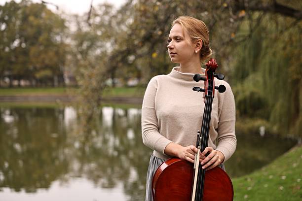 istock Beautiful young woman with cello in park, space for text 2211897312