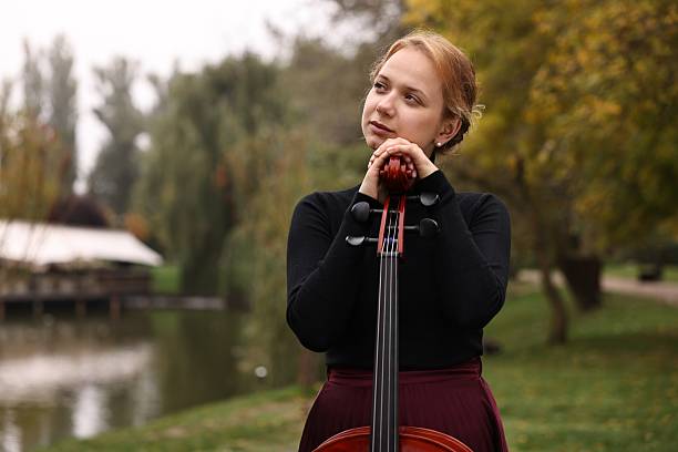 istock Beautiful young woman with cello in park 2211897352
