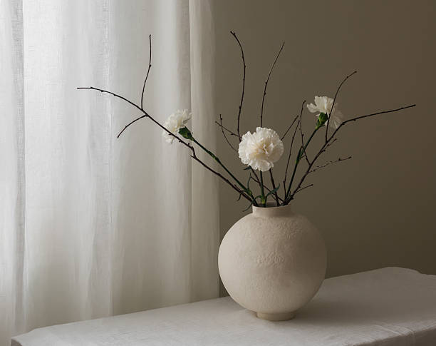 istock A composition of white carnations and dried branches in a ceramic round vase on a white table 2211898245
