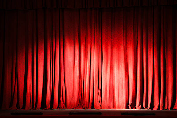 istock Elegant closed red curtains illuminated by spotlight in theatre 2211899218