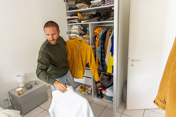 istock Man Organizing Clothes in Open Wardrobe Closet 2211900081