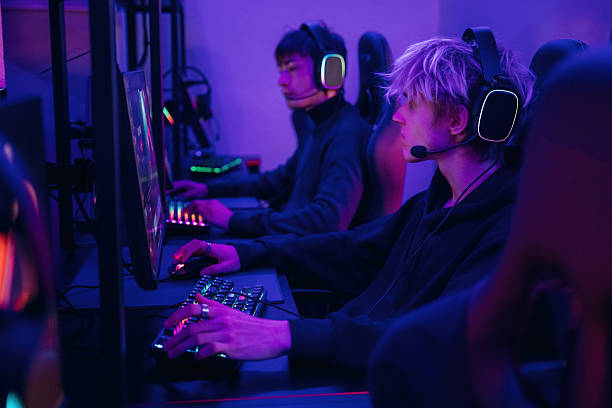 istock Side view. Gamers are playing video game by computers 2211900192
