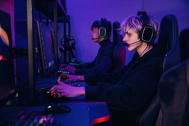istock Side view. Gamers are playing video game by computers 2211900194