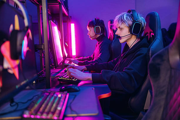 istock Side view. Gamers are playing video game by computers 2211900203