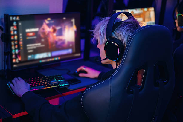 istock Sitting and focused. Gamers are playing video game by computers 2211900215