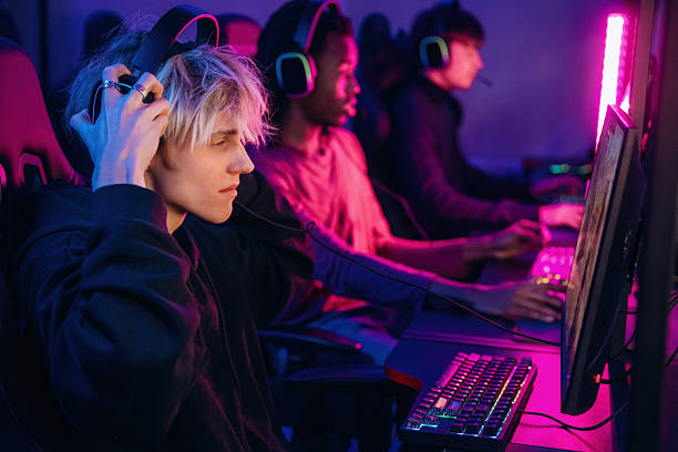 istock View from the side, sitting. Gamers are playing video game by computers 2211900461