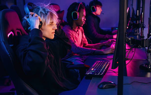 istock View from the side, sitting. Gamers are playing video game by computers 2211900469