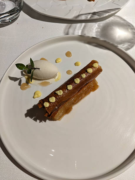 istock A plated dessert featuring a pastry roll with ice cream and garnishes, presented beautifully for gourmet dining. 2211900498