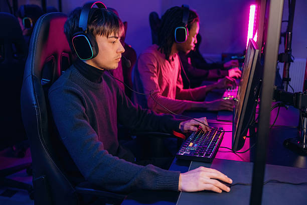 istock Neon colors in the room. Gamers are playing video game by computers 2211900519