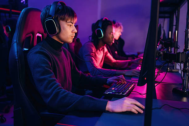 istock Neon colors in the room. Gamers are playing video game by computers 2211900548