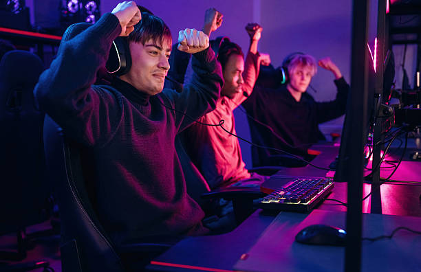 istock Celebrating victory. Gamers are playing video game by computers 2211900551