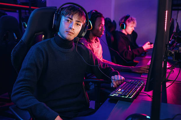 istock Neon colors in the room. Gamers are playing video game by computers 2211900559