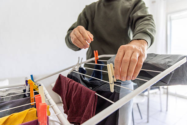 istock Person Hanging Clothes on Indoor Drying Rack 2211900897