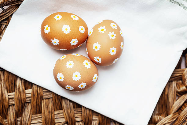 Easter eggs of natural color with painted tiny flowers a white waffle towel. Creative easy idea of decorating eggs. Neutral colors, aesthetics. Selective focus.