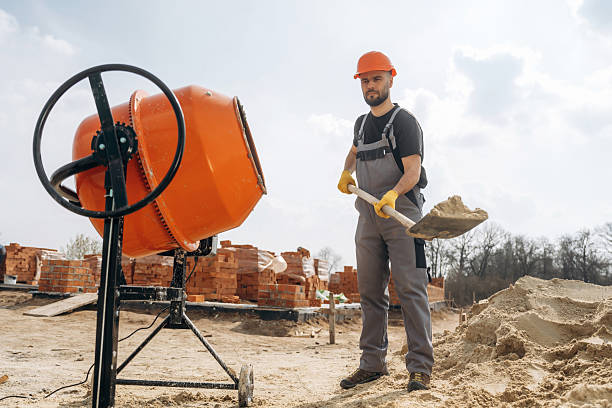 istock Shovel in hands. Man is working on the construction site with concrete mixer 2211910645
