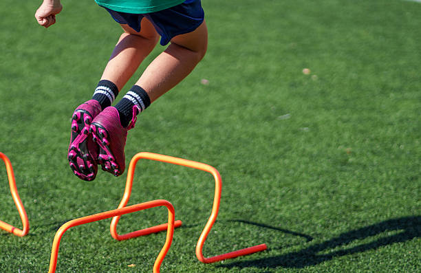 istock Soccer player jumping over orange mini hurdles on turf field 2211910725