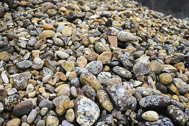 Pebble riverbank near a clear mountain stream with fresh water and lush green surroundings.