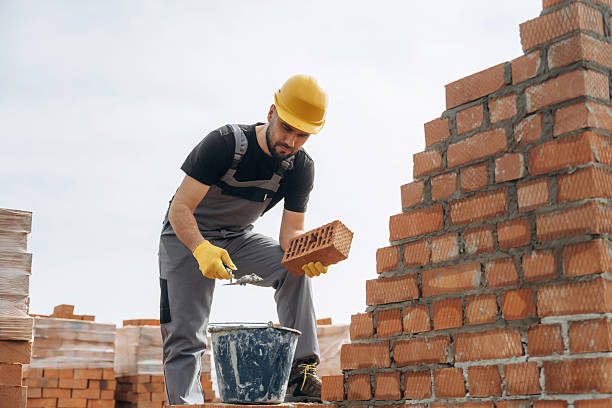 istock In uniform and hard hat. Construction worker is at job with bricks outdoors 2211912643