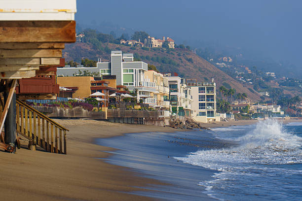 Malibu, California - December 21, 2024: Peaceful view of Malibu's stunning beachfront, showcasing beautiful coastal homes and gentle ocean waves under a bright sky.