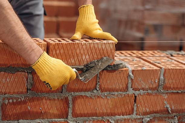 istock In yellow gloves. Close up view of construction man that is working with bricks 2211912891