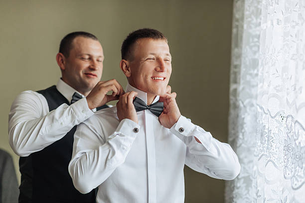 istock Two men are getting dressed up, one of them is wearing a bow tie 2211913283