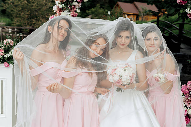 istock A bride and her bridesmaids are hiding behind a white veil 2211913308