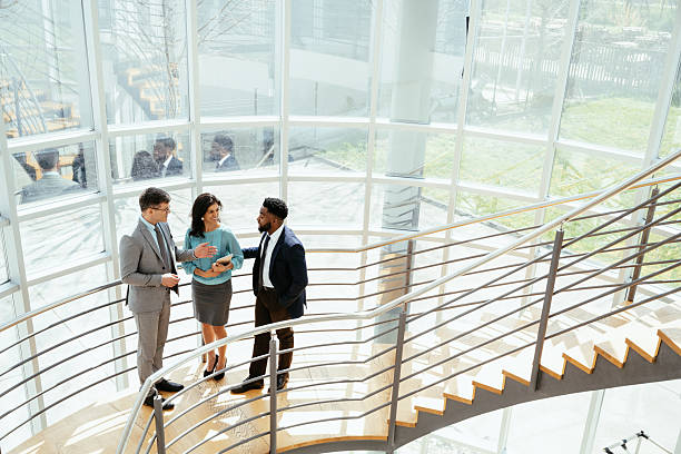 istock Multicultural corporate business people working in modern bright office on laptops and tablets, standing in the corridor with large windows 2211913970