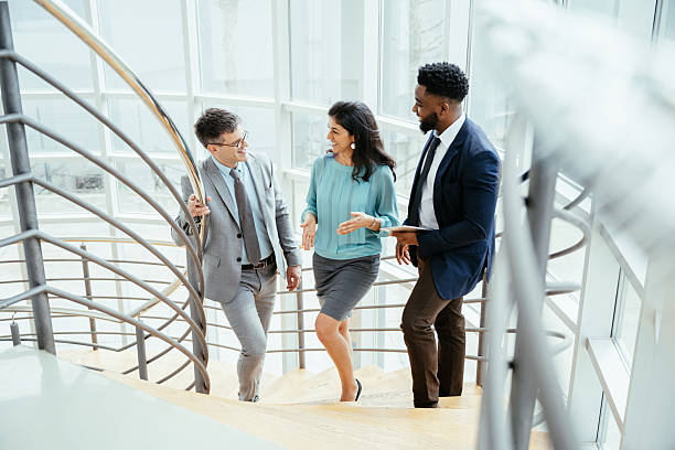 istock Multicultural corporate business people working in modern bright office on laptops and tablets, standing in the corridor with large windows 2211914020