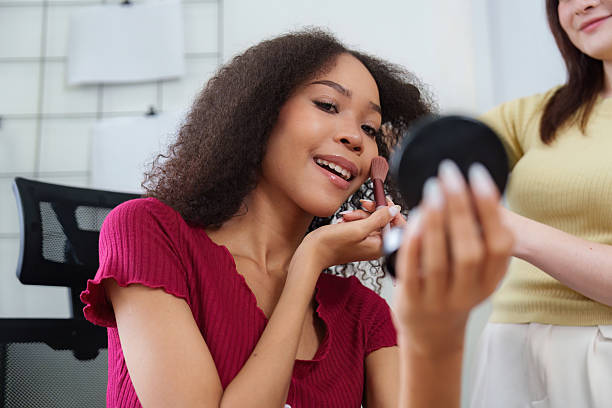 istock Makeup Application and Diversity. A woman applying blush while enjoying a makeup session with a friend. 2211915625