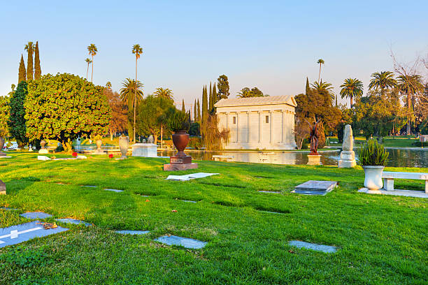 Los Angeles, California - January 10, 2025: Serene view of Hollywood Forever Cemetery featuring palm trees, manicured lawns, and elegant mausoleums illuminated by soft evening light in Los Angeles, California.