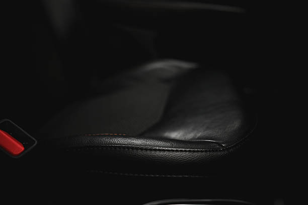 Empty black leather car seat with red seat belt buckle