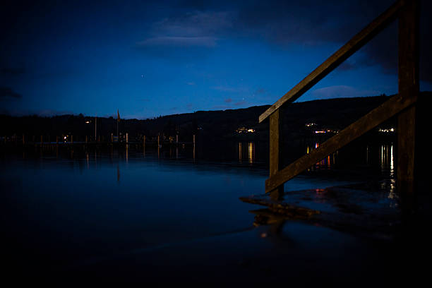 Lake shot at night, clear sky. Steps from dock leading down into the water.