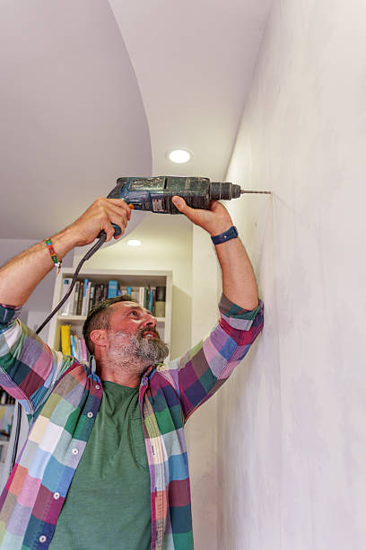 istock Handyman drilling a hole in the wall using a drill 2211923082