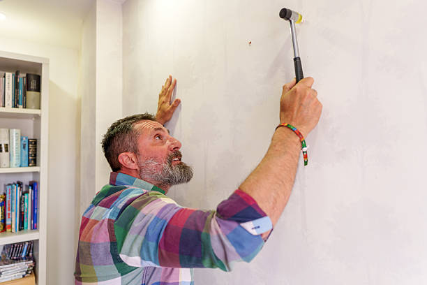 istock Man hammering nail into wall at home 2211923087
