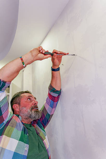 istock Handyman tightening a screw into the wall using a screwdriver 2211923125