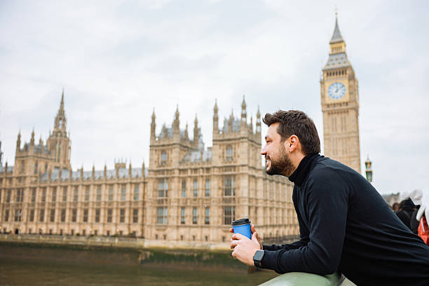 istock Young man drinking coffee in a disposable cup on Westminster Bridge 2211923921