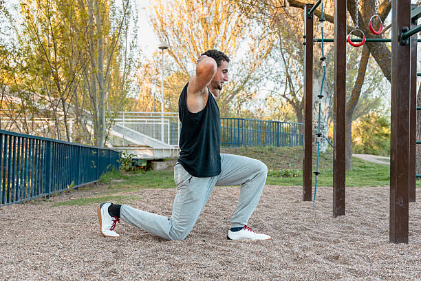 istock Man performing bodyweight lunge with hands behind head outdoors, targeting leg strength, posture, and lower body mobility in a calisthenics environment 2211923983