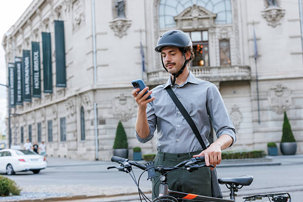 istock Businessman with a bicycle using smartphone outside an urban building 2211924117