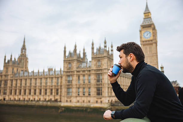 istock Young man drinking coffee in a disposable cup on Westminster Bridge 2211926117
