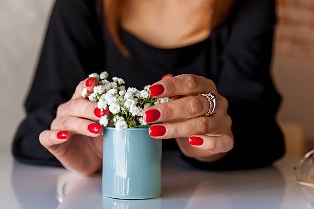 istock Womans hands with red nails holding small flower vase 2211927007