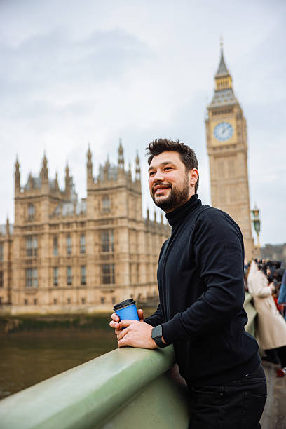 istock Young man drinking coffee in a disposable cup on Westminster Bridge 2211927737