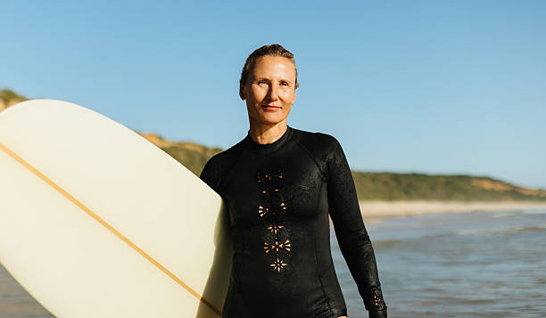 istock Mature female surfer posing with a surfboard on a sunny beach 2211934060