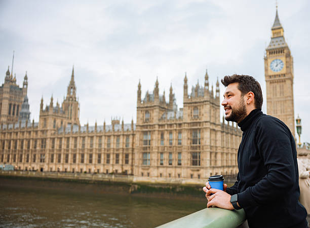 istock Young man drinking coffee in a disposable cup on Westminster Bridge 2211934369